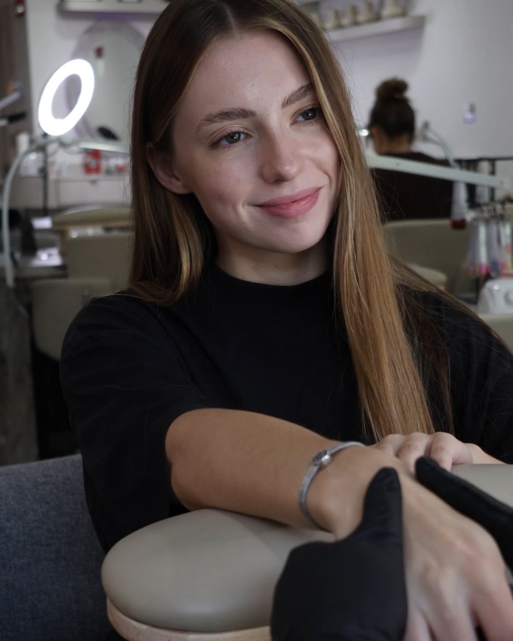 A guest smiling at a nail station in the salon